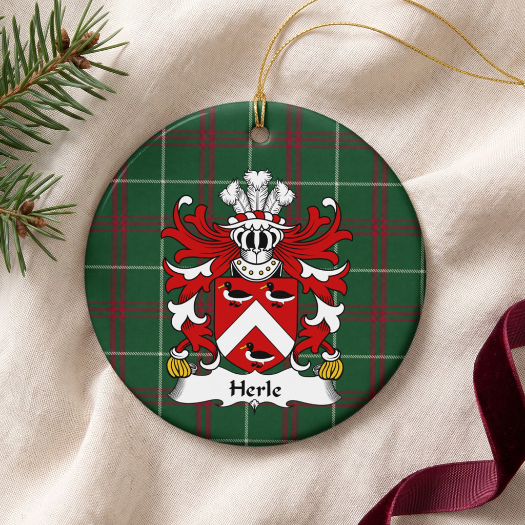 Herle ornament on cream fabric beside evergreen and burgundy ribbon, with gold string; three black-and-white ducks around a white chevron on a red shield.