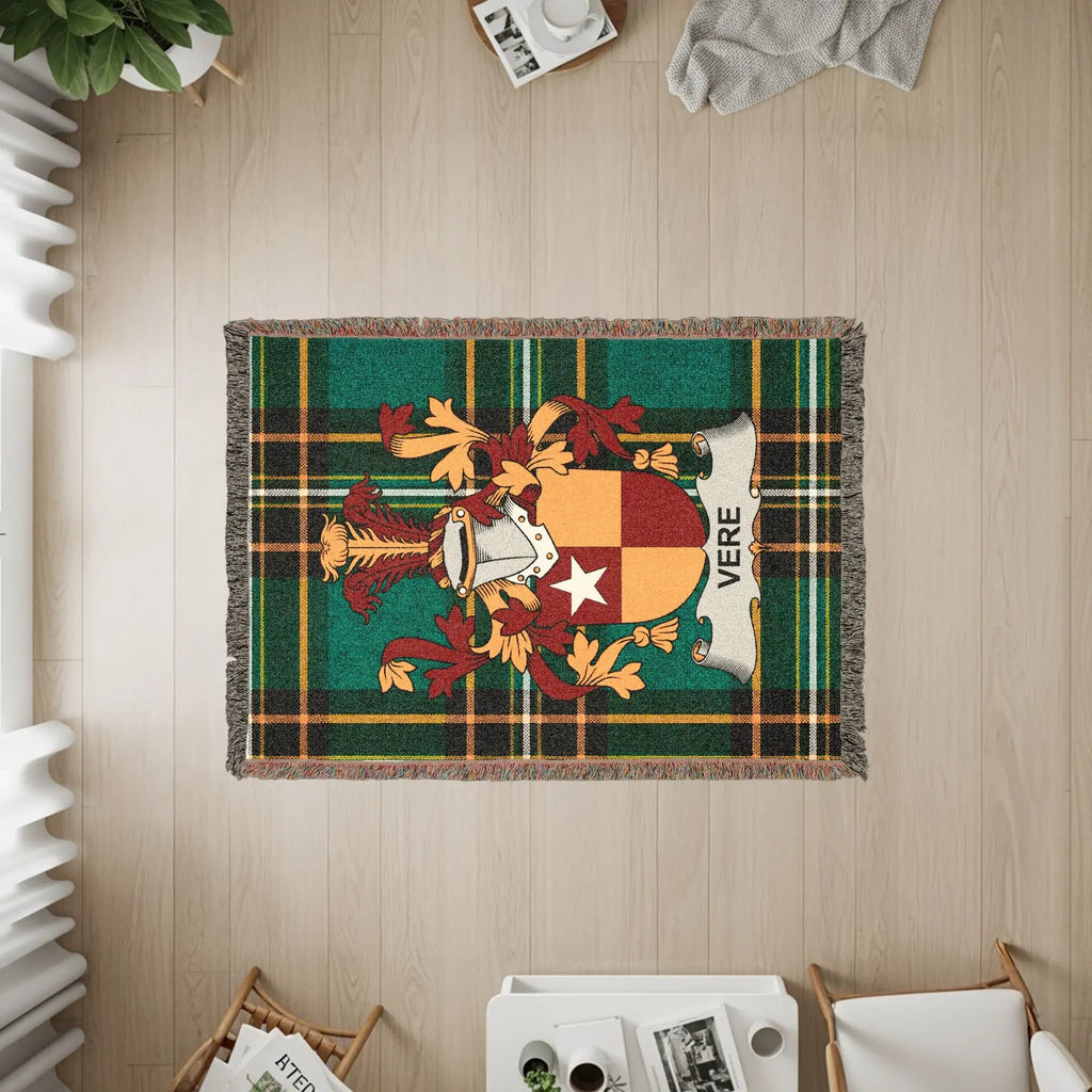 Woven blanket with Vere family crest on green plaid background.