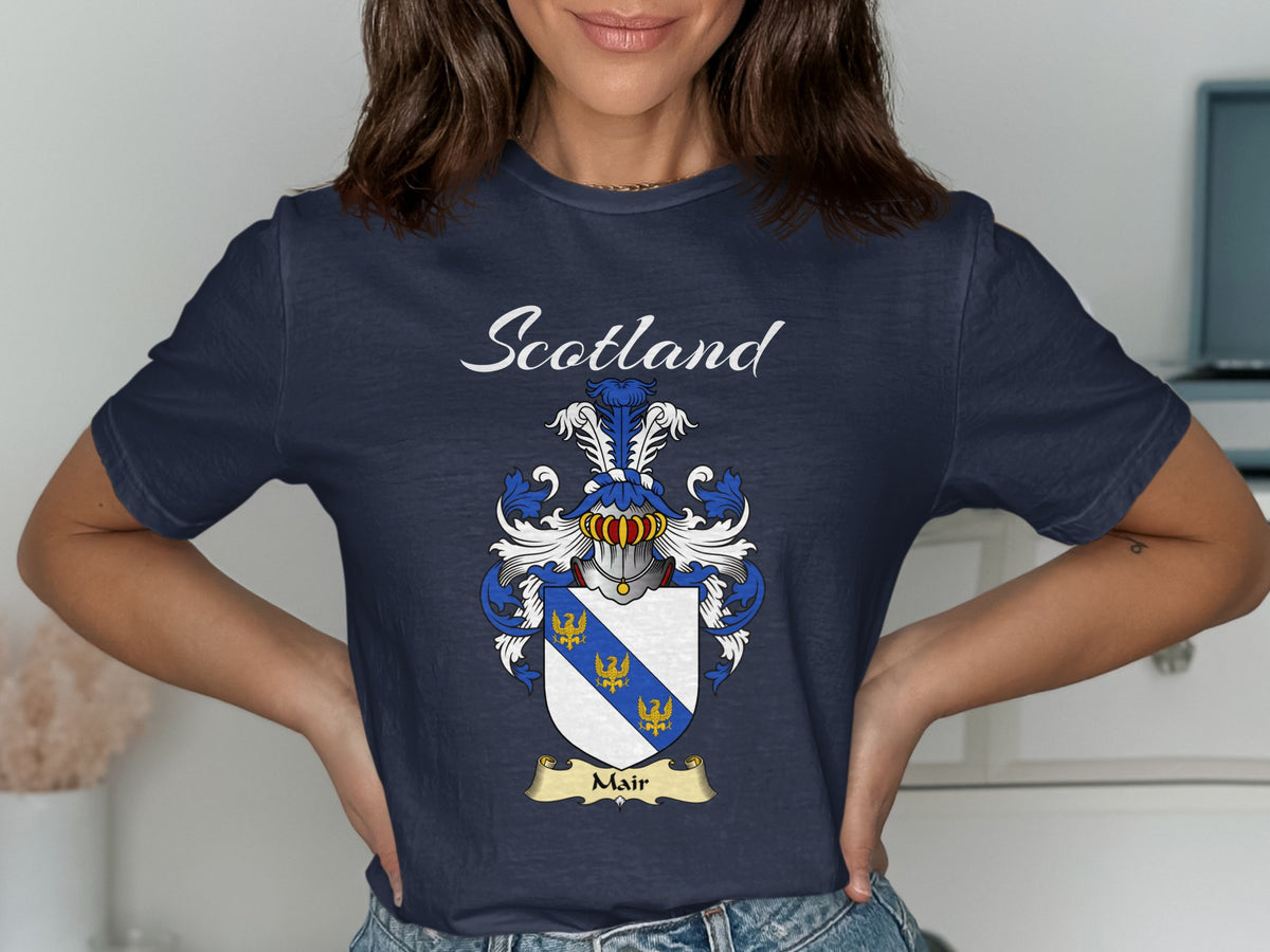 Model wearing a navy Mair T-shirt featuring a blue diagonal band with small gold motifs