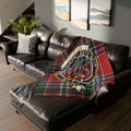 MacBean tartan blanket with crest draped over a brown leather sectional sofa.