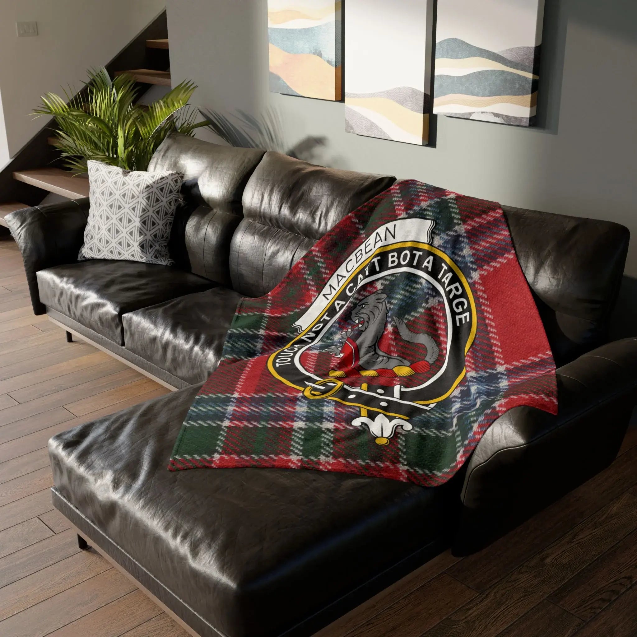 MacBean tartan blanket with crest draped over a brown leather sectional sofa.