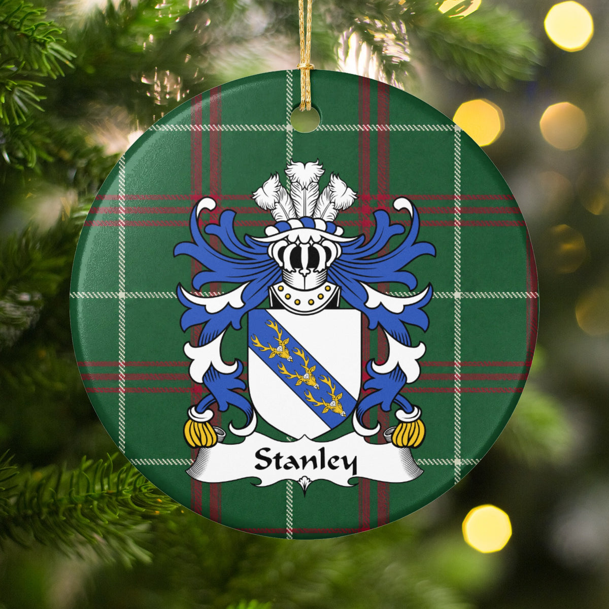 Stanley family crest ornament with Welsh national tartan background, hanging by a gold cord among Christmas tree branches and warm lights.