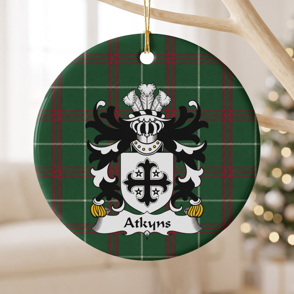 Atkyns ornament hanging from a pale branch; a black decorative cross surrounded by four small black stars on white on Welsh national tartan.