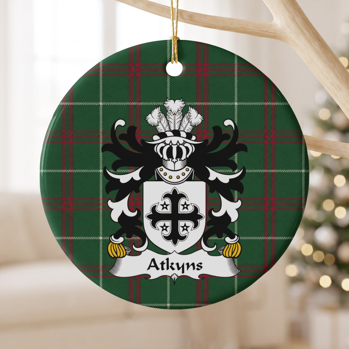 Atkyns ornament hanging from a pale branch; a black decorative cross surrounded by four small black stars on white on Welsh national tartan.