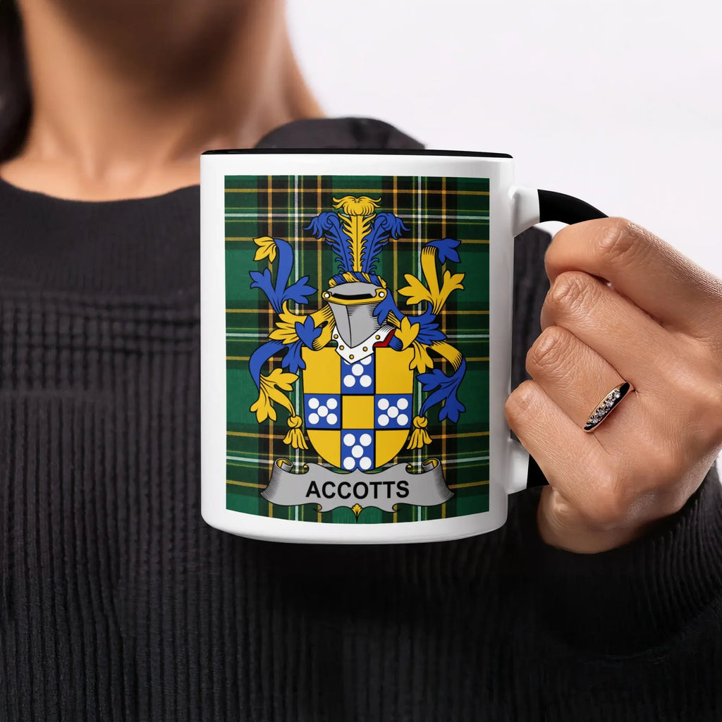 A black mug with a green, blue, and yellow plaid design and the name "ACCOTTS" in gold.