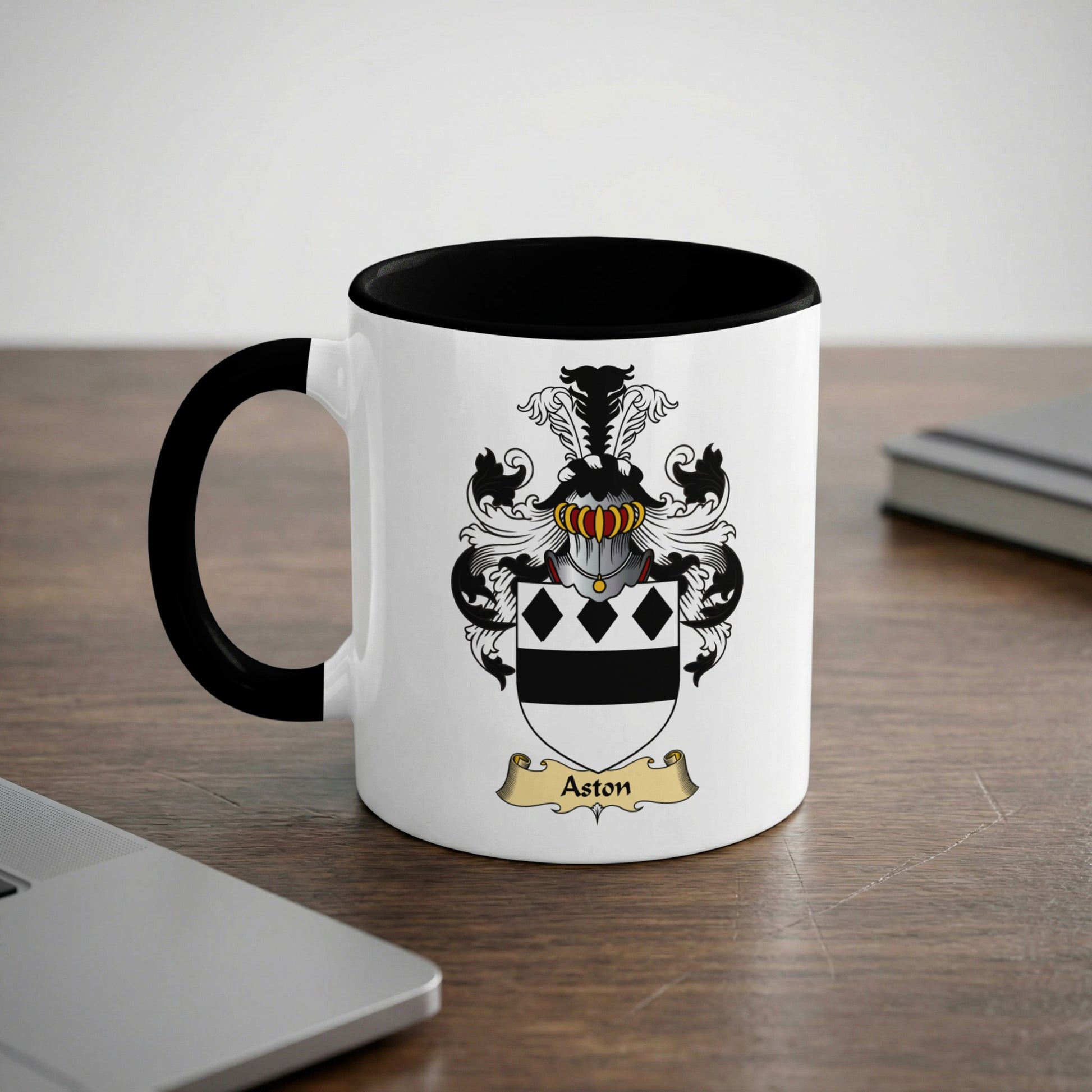 White mug with black rim and handle, featuring the Aston family crest.
