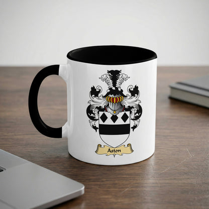 White mug with black rim and handle, featuring the Aston family crest.
