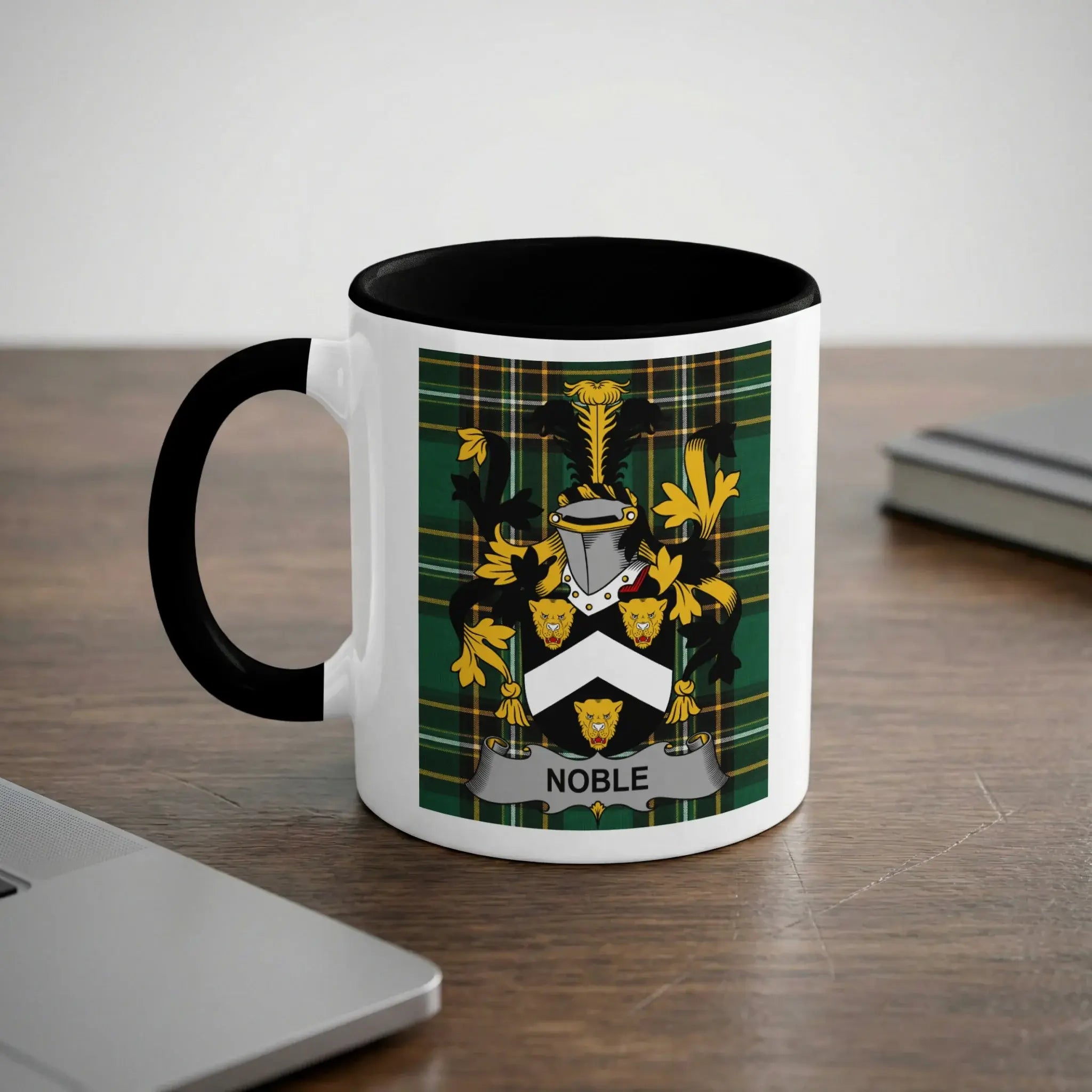 White mug with black rim featuring a green plaid crest with the word "Noble."