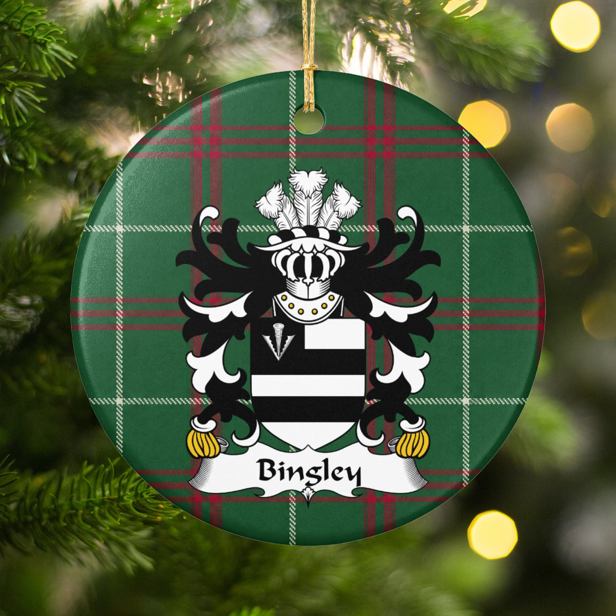 Bingley ornament hanging in a Christmas tree with warm lights; two black bars on white with a white arrowhead in a black corner panel on Welsh national tartan.