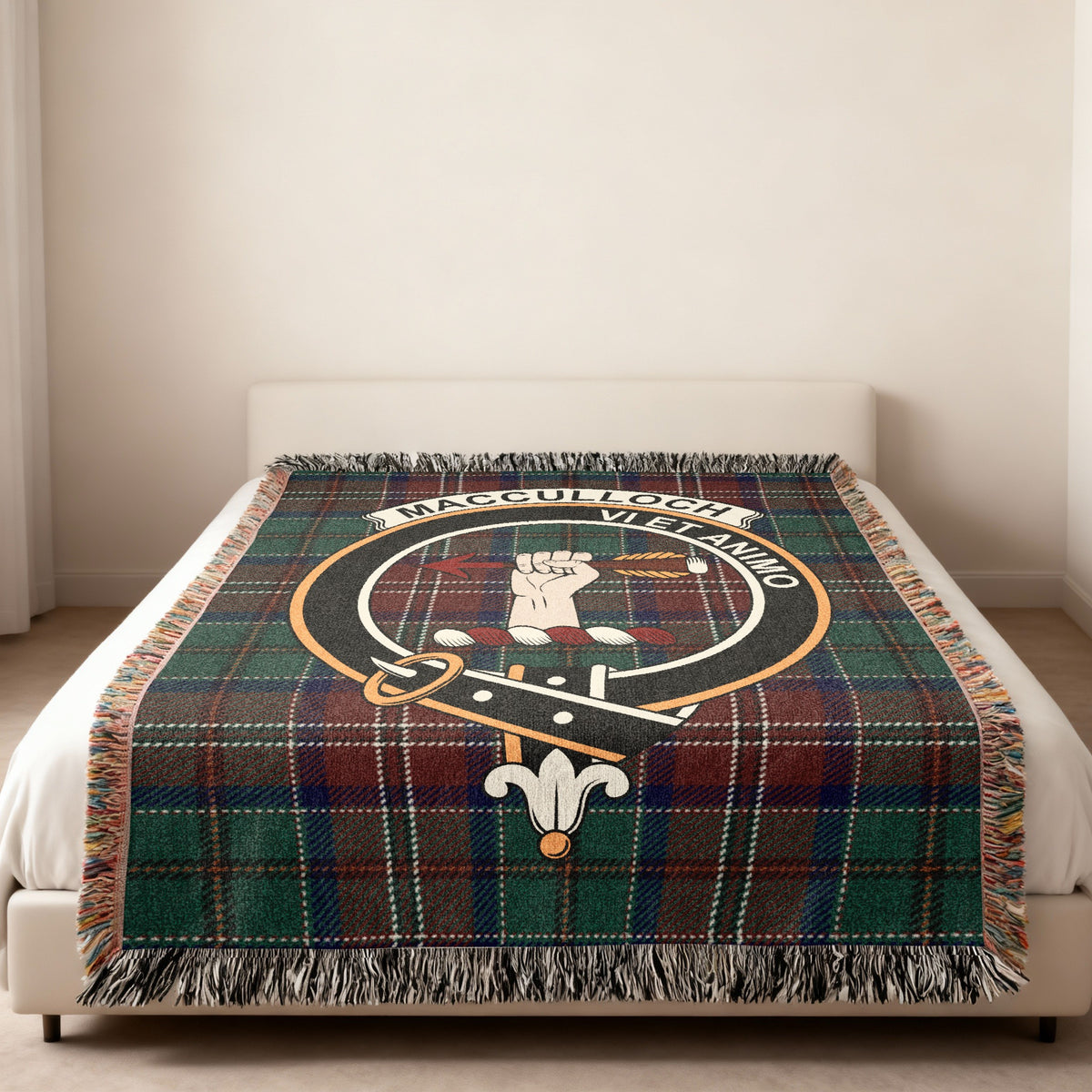 MacCulloch Scottish woven blanket spread across a bed, showing the full crest design and tartan background