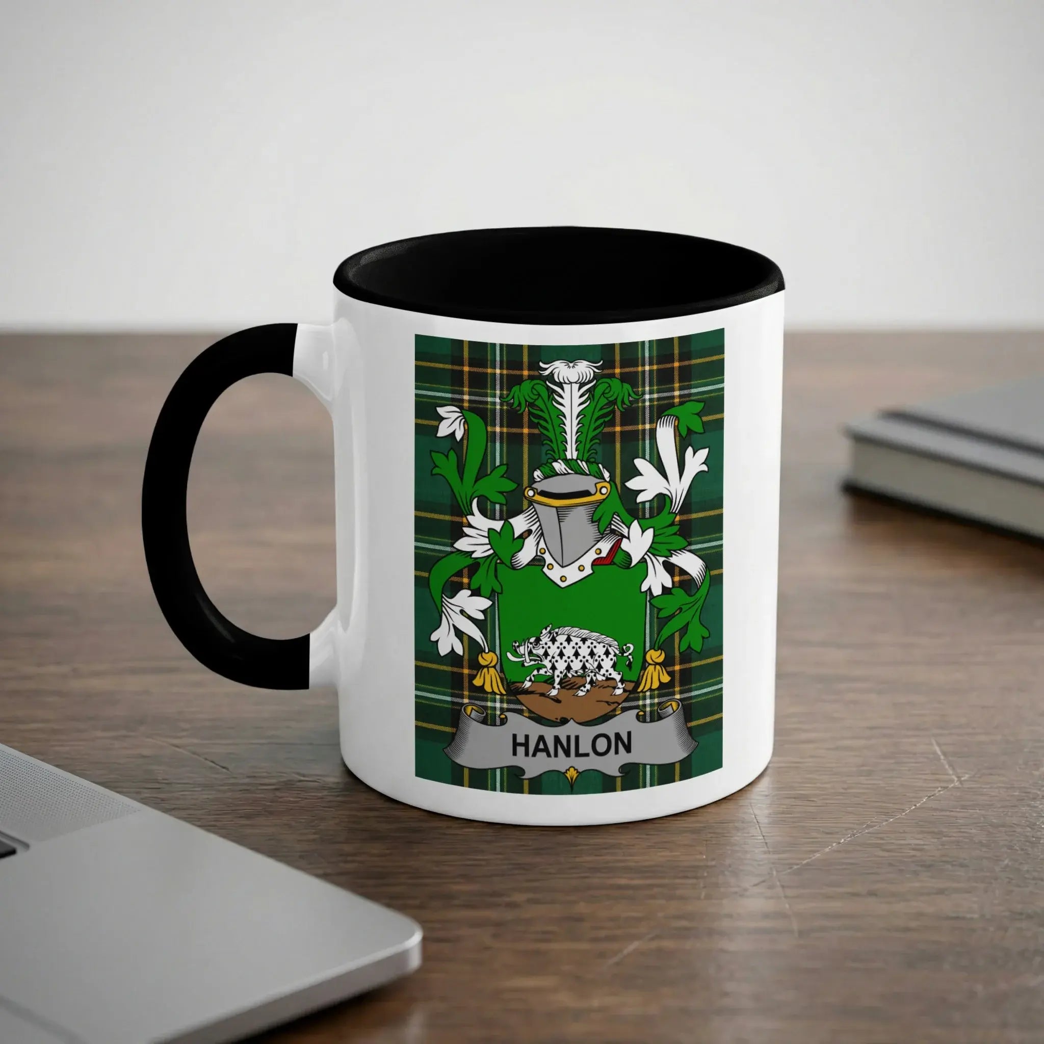 White mug with black rim featuring a green and yellow family crest with the name "HANLON".