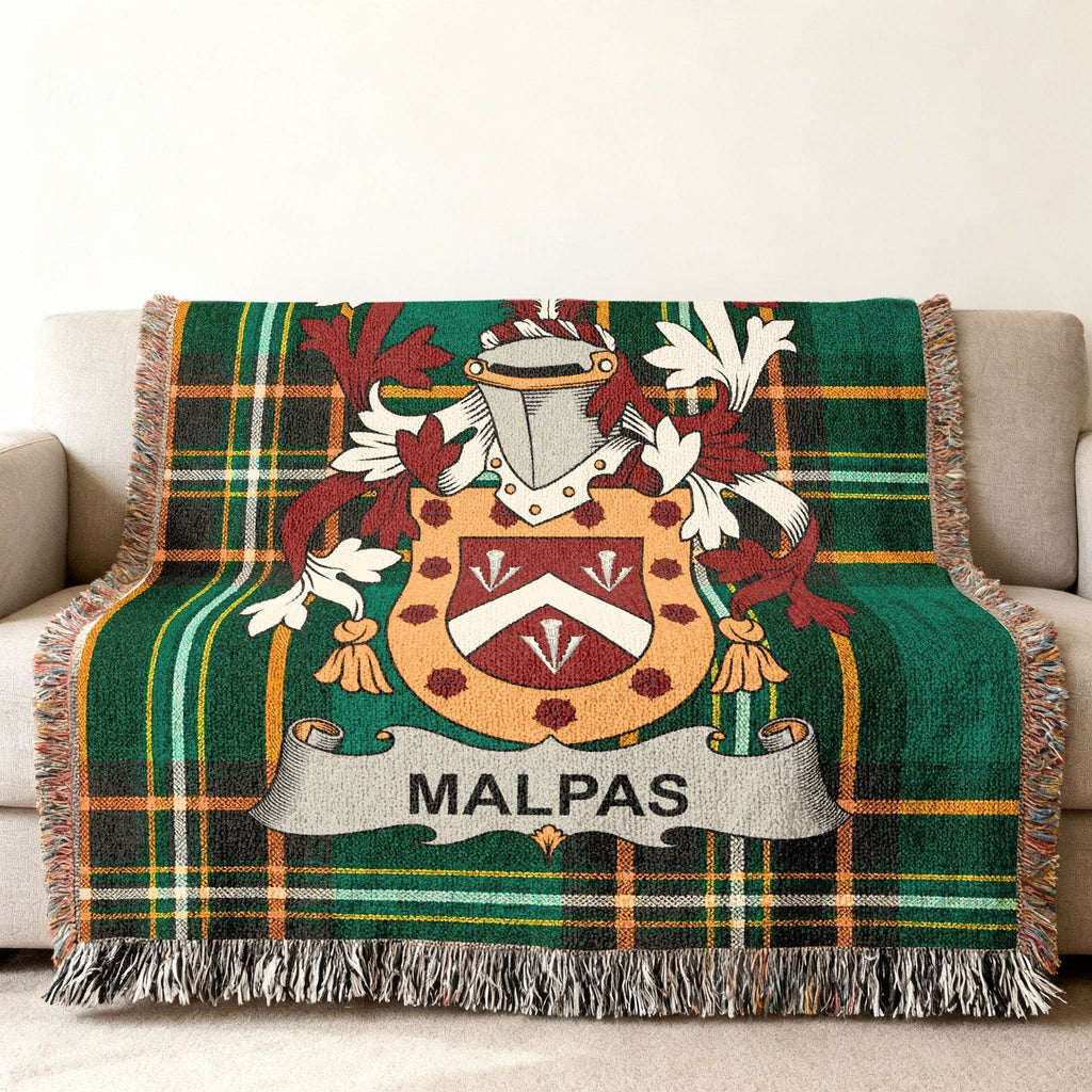 Green plaid throw blanket with Malpas family crest on a couch.