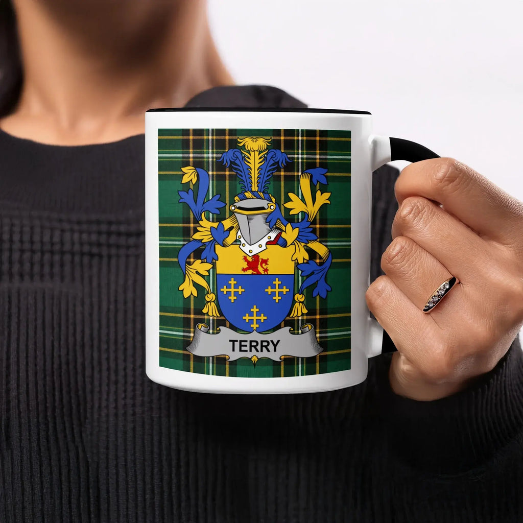Terry family crest on a black and white mug held by a person.