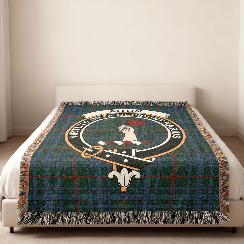 Aiton Scottish woven blanket spread across a bed, showing the full crest design and tartan background