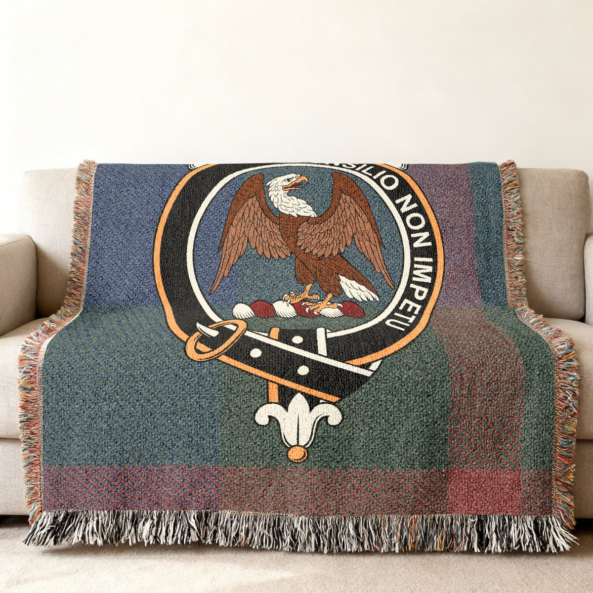 Close view of the Agnew woven blanket draped over a sofa, showing the crest and fringed edges