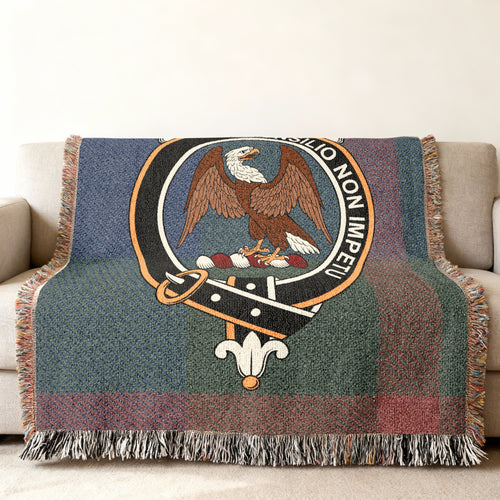 Close view of the Agnew woven blanket draped over a sofa, showing the crest and fringed edges
