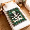 Green tartan blanket with crest and "Pugh" surname on a bed.