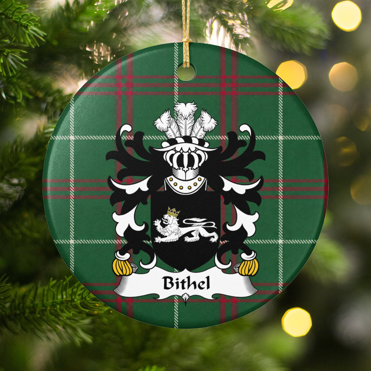 Bithel ornament hanging in a Christmas tree with warm lights; a white reclining lion with a gold crown on black on Welsh national tartan.