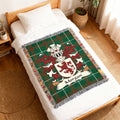 Green tartan throw blanket with Morgan family crest and lion emblem.