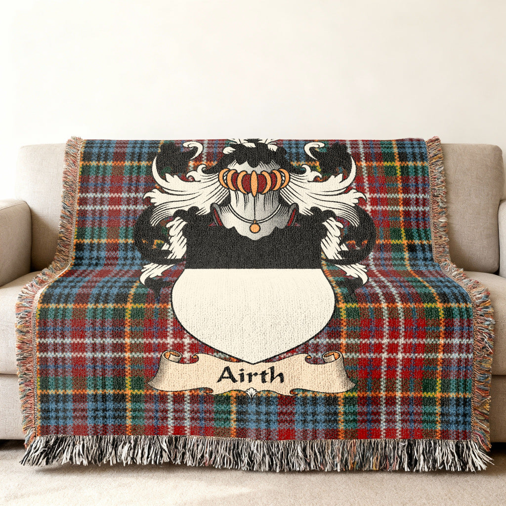 Airth Scottish family shield woven blanket with Caledonia tartan background on a sofa