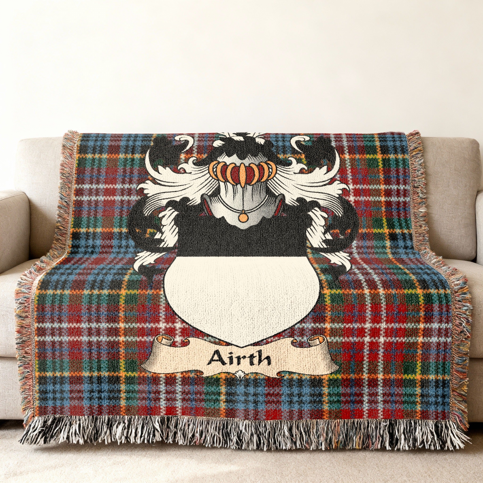 Airth Scottish family shield woven blanket with Caledonia tartan background on a sofa