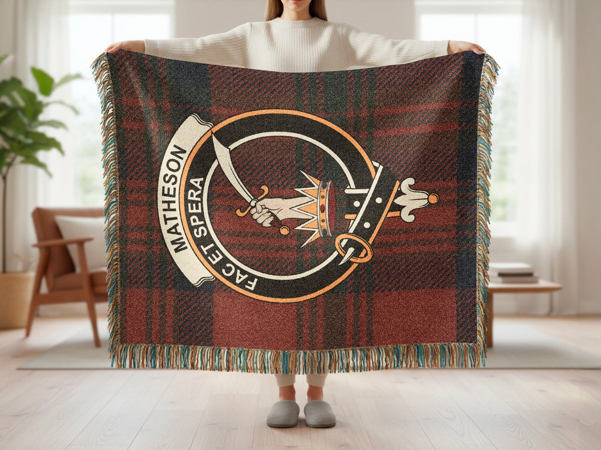 Person holding the Matheson woven blanket to show the full design, tartan background and fringe
