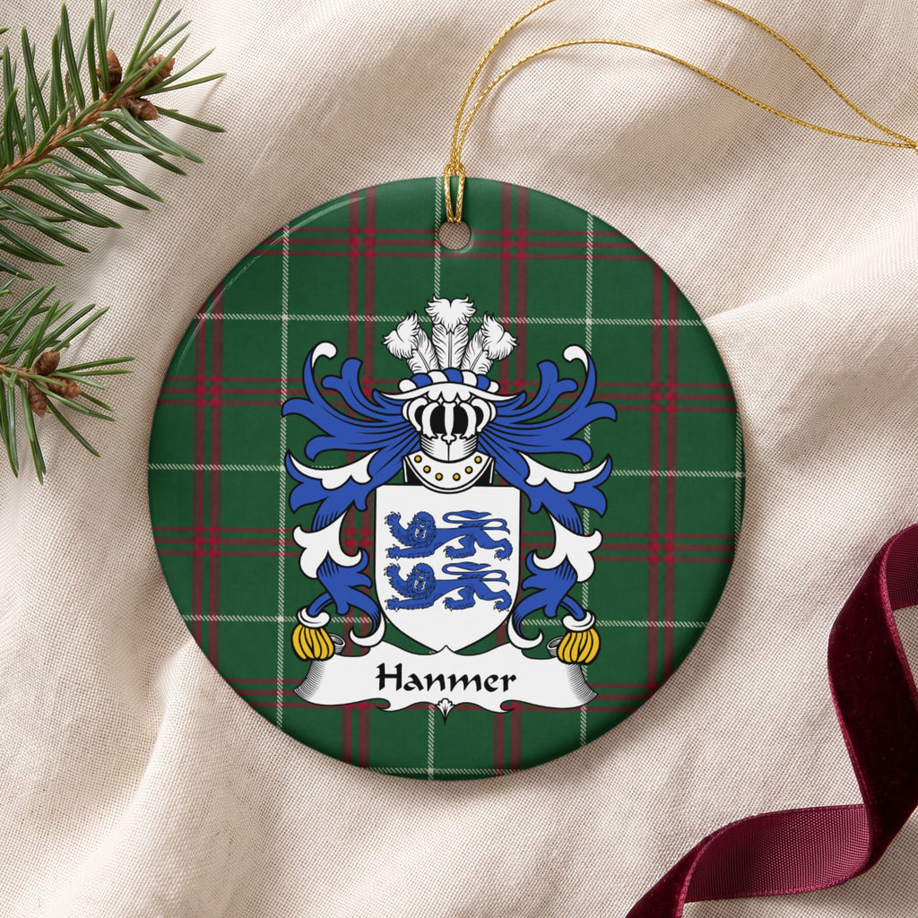 Hanmer ornament on cream fabric beside evergreen and burgundy ribbon, with gold string; two blue lions on a white shield.