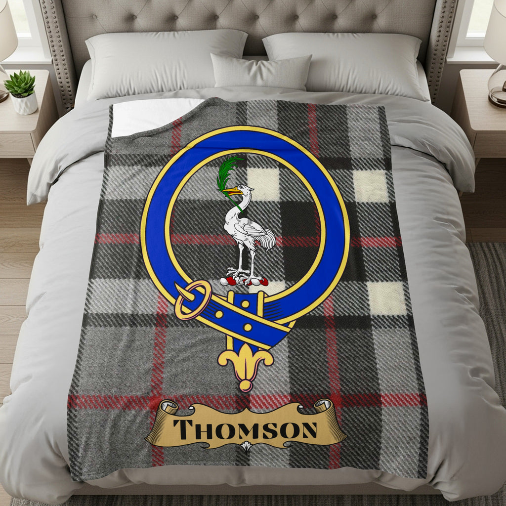 Thomson clan tartan throw with crest and name on a bed