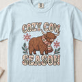 Cozy Cow Season Highland cow design on a Chambray Comfort Colors 1717 T-shirt, flat lay