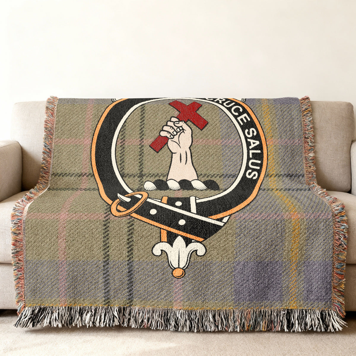 Close view of the Tailyour woven blanket draped over a sofa, showing the crest and fringed edges