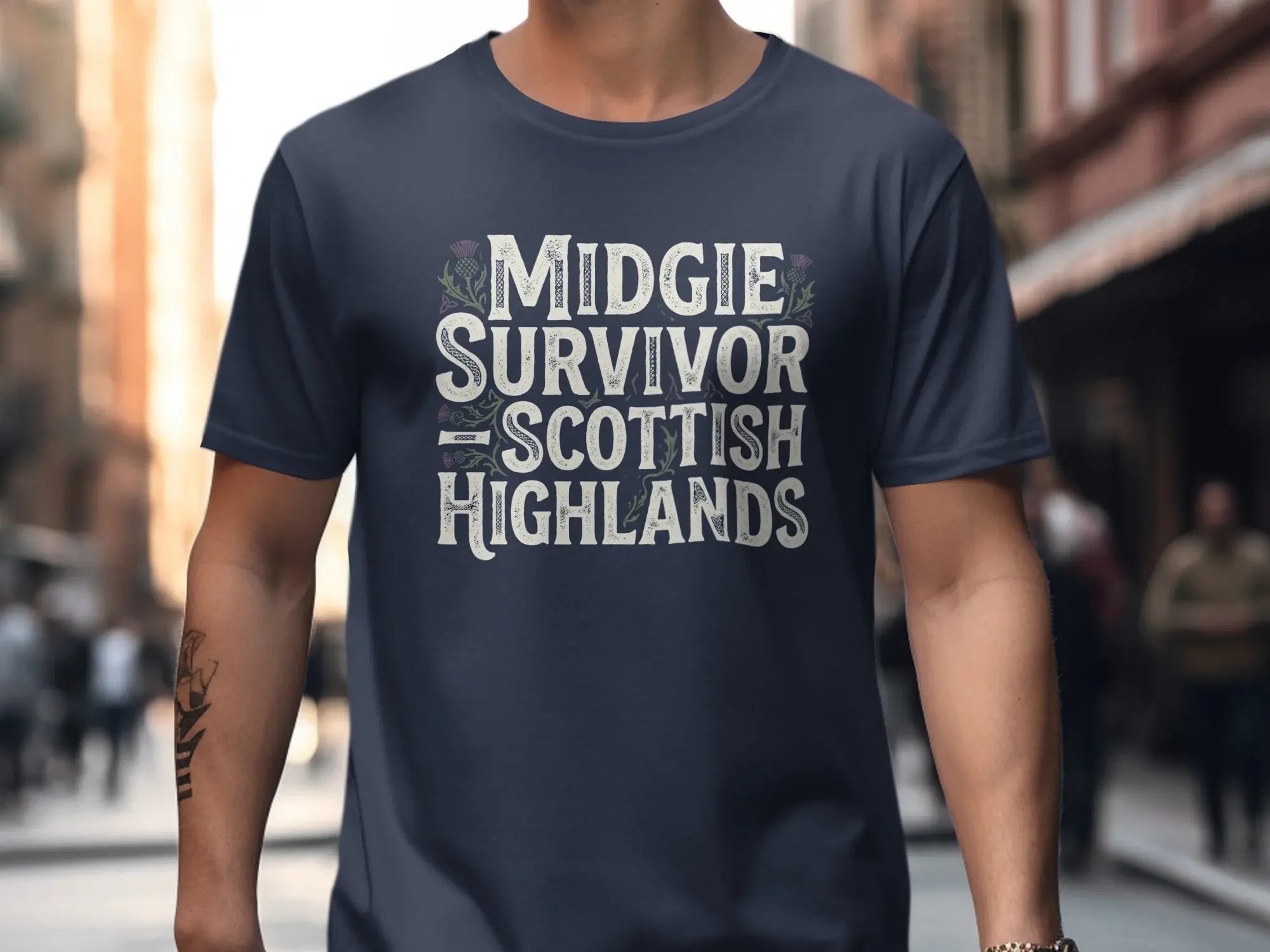 Dark blue t-shirt with "Midgie Survivor Scottish Highlands" text and thistle graphics.
