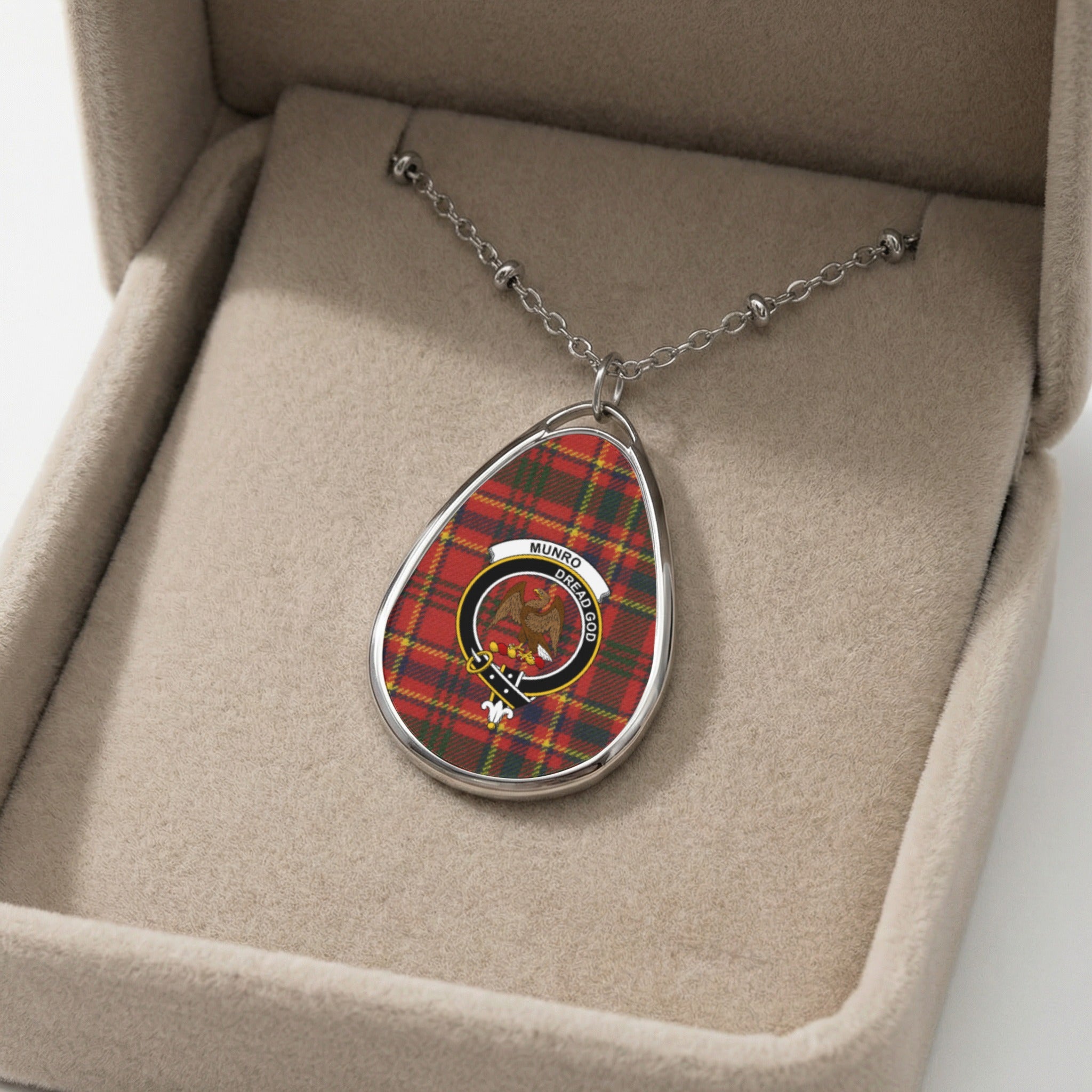 Oval pendant necklace with red and green plaid and Munro clan crest in a jewelry box.