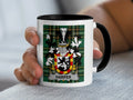 White mug with black rim featuring the Harper family crest on a tartan background.