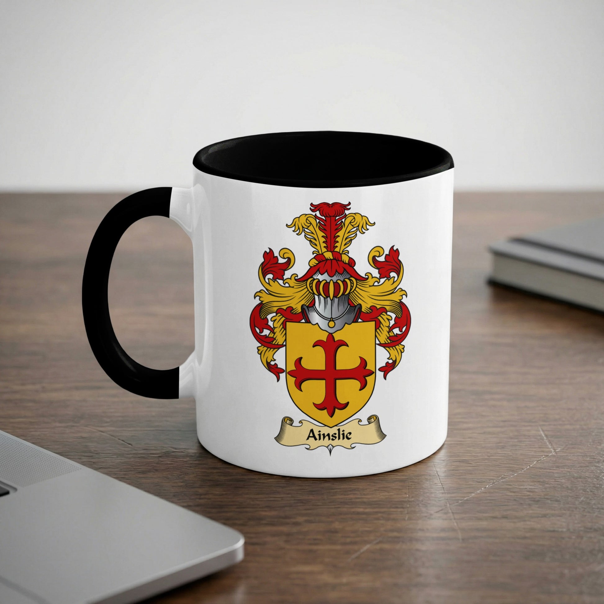 White mug with black rim and handle, featuring the Ainslie coat of arms.