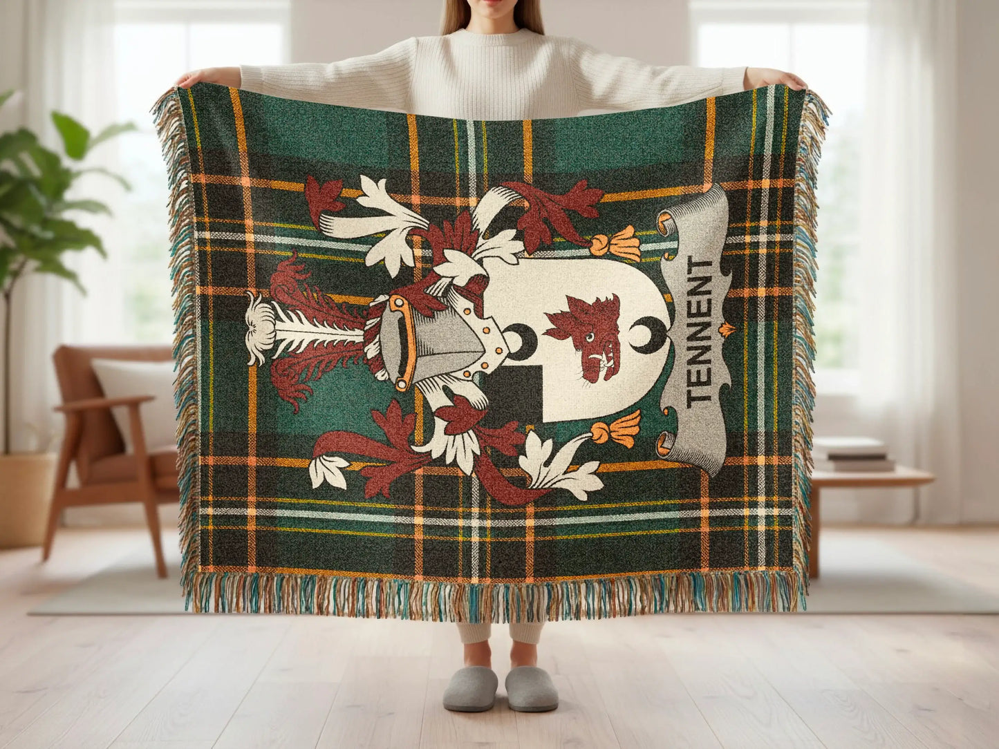 Tartan blanket with Tennent family crest and tassels held by a person.