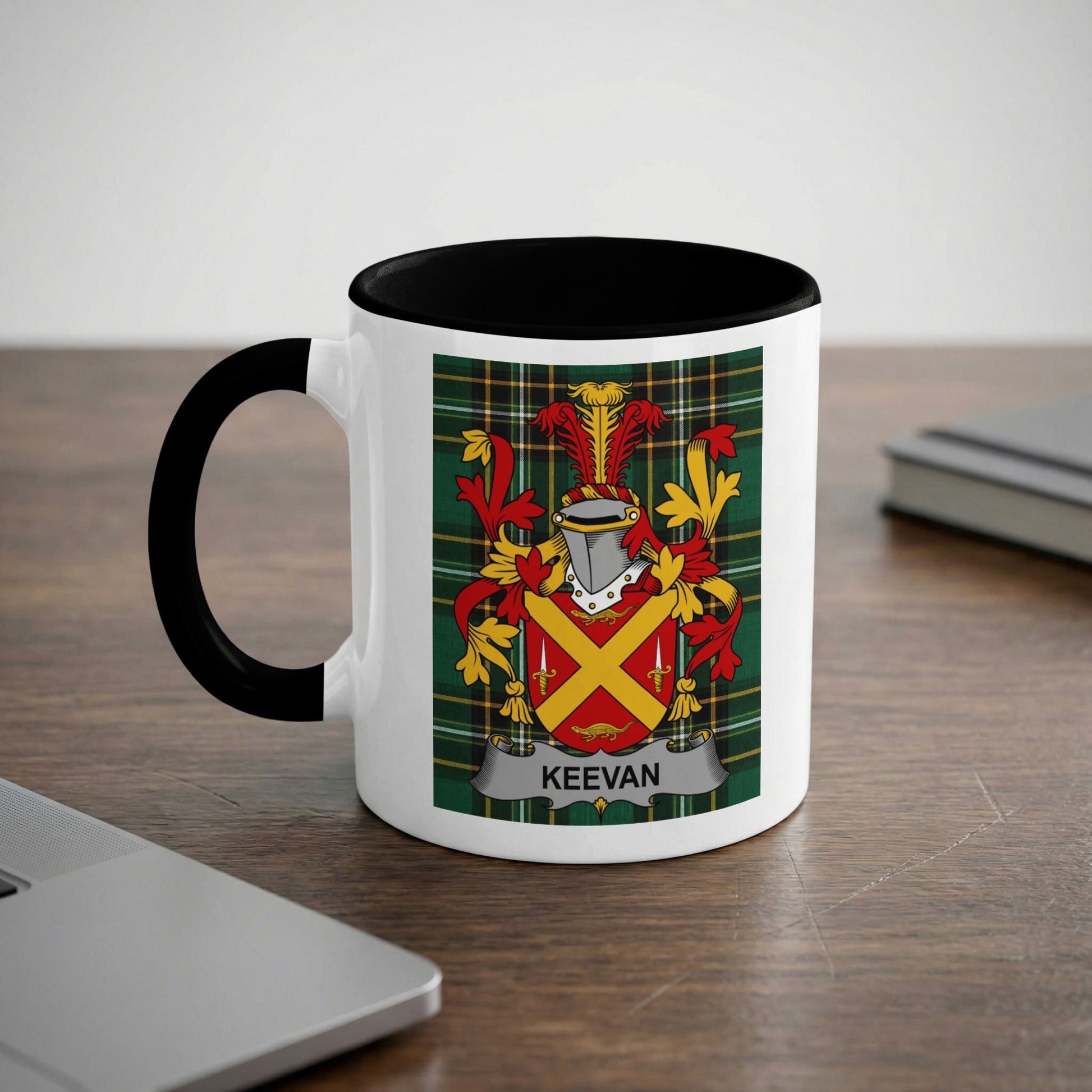 Mug with the Keevan family crest on a desk next to a laptop.