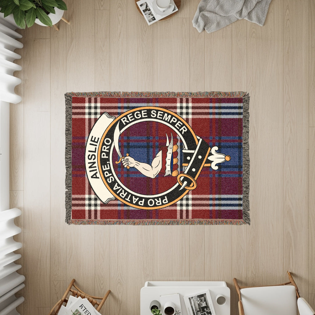 Ainslie woven blanket displayed on a wall, featuring the crest badge and tartan background