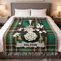 Tartan blanket with Hilton crest draped on a bed.