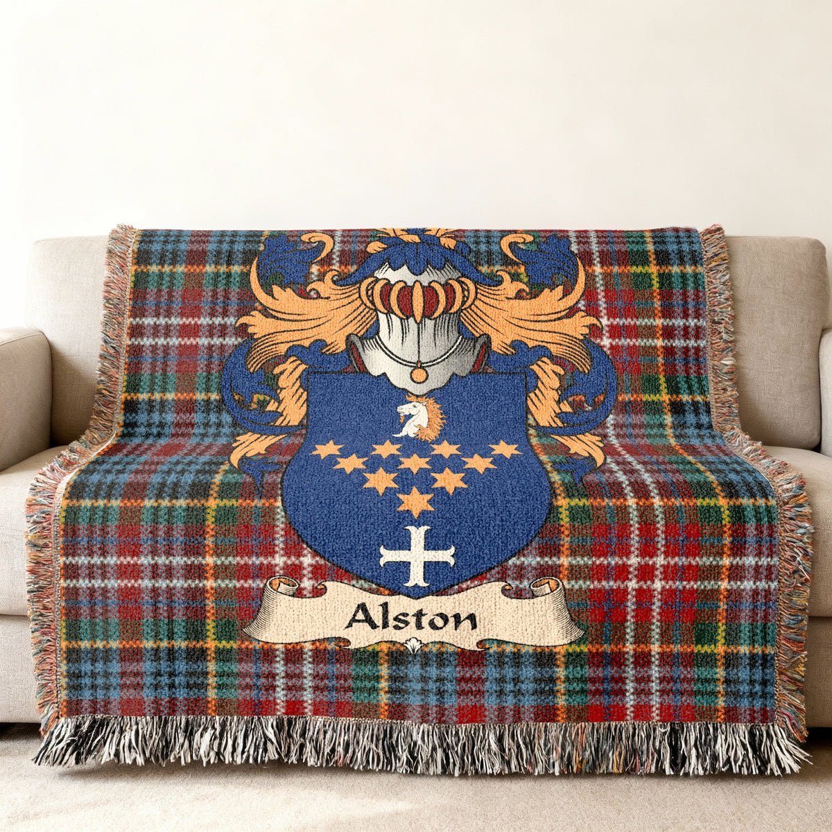 Alston Scottish family shield woven blanket with Caledonia tartan background on a sofa