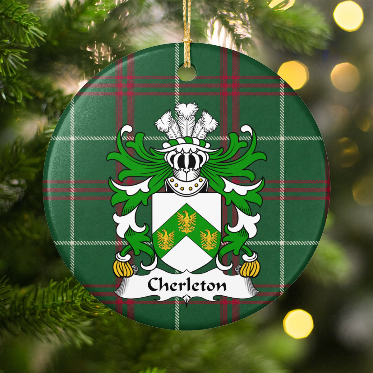 Cherleton ornament hanging among Christmas tree branches and warm lights; three gold birds on a green chevron across a white shield on Welsh national tartan.
