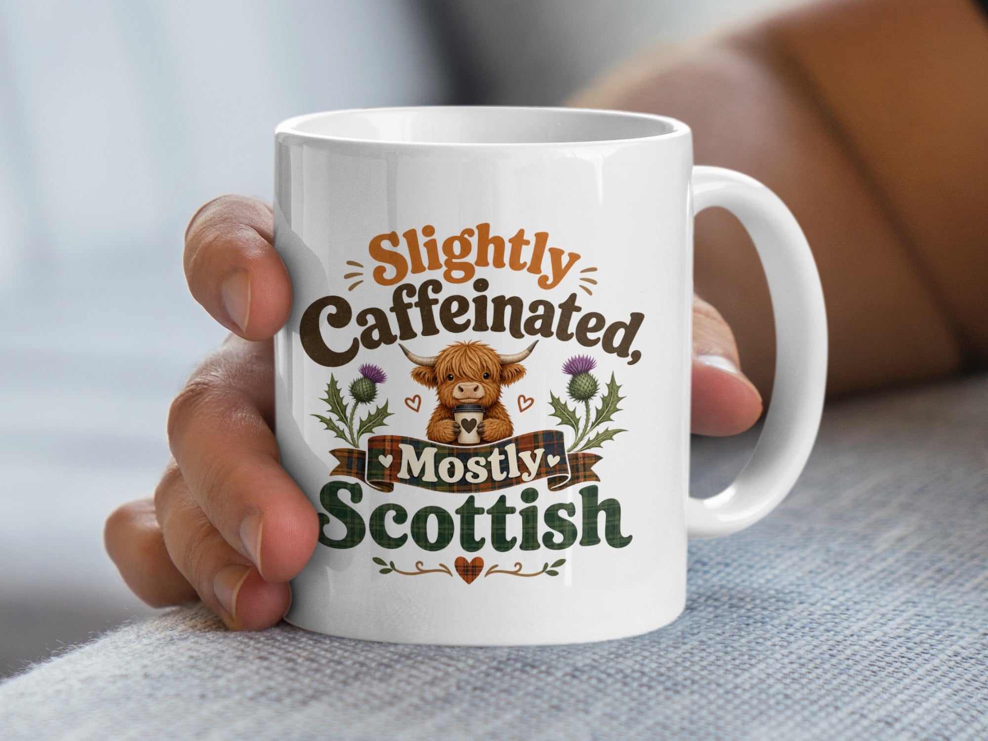 White mug with "Slightly Caffeinated, Mostly Scottish" and Highland cow graphic.