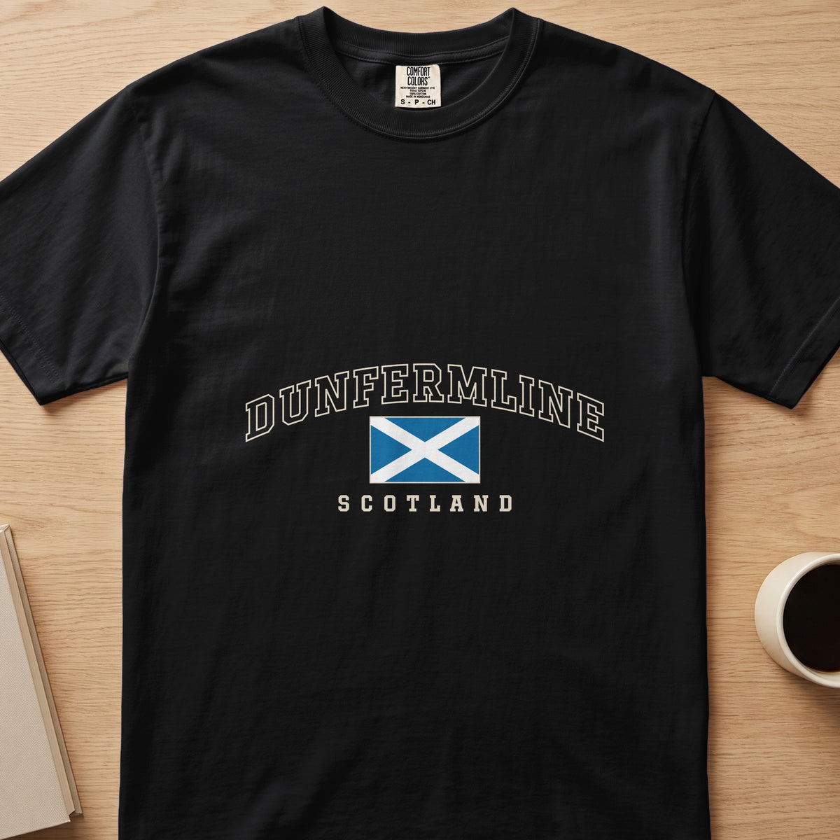 Black Dunfermline Scotland Comfort Colors T-shirt laid flat, showing cream collegiate lettering and the Saltire