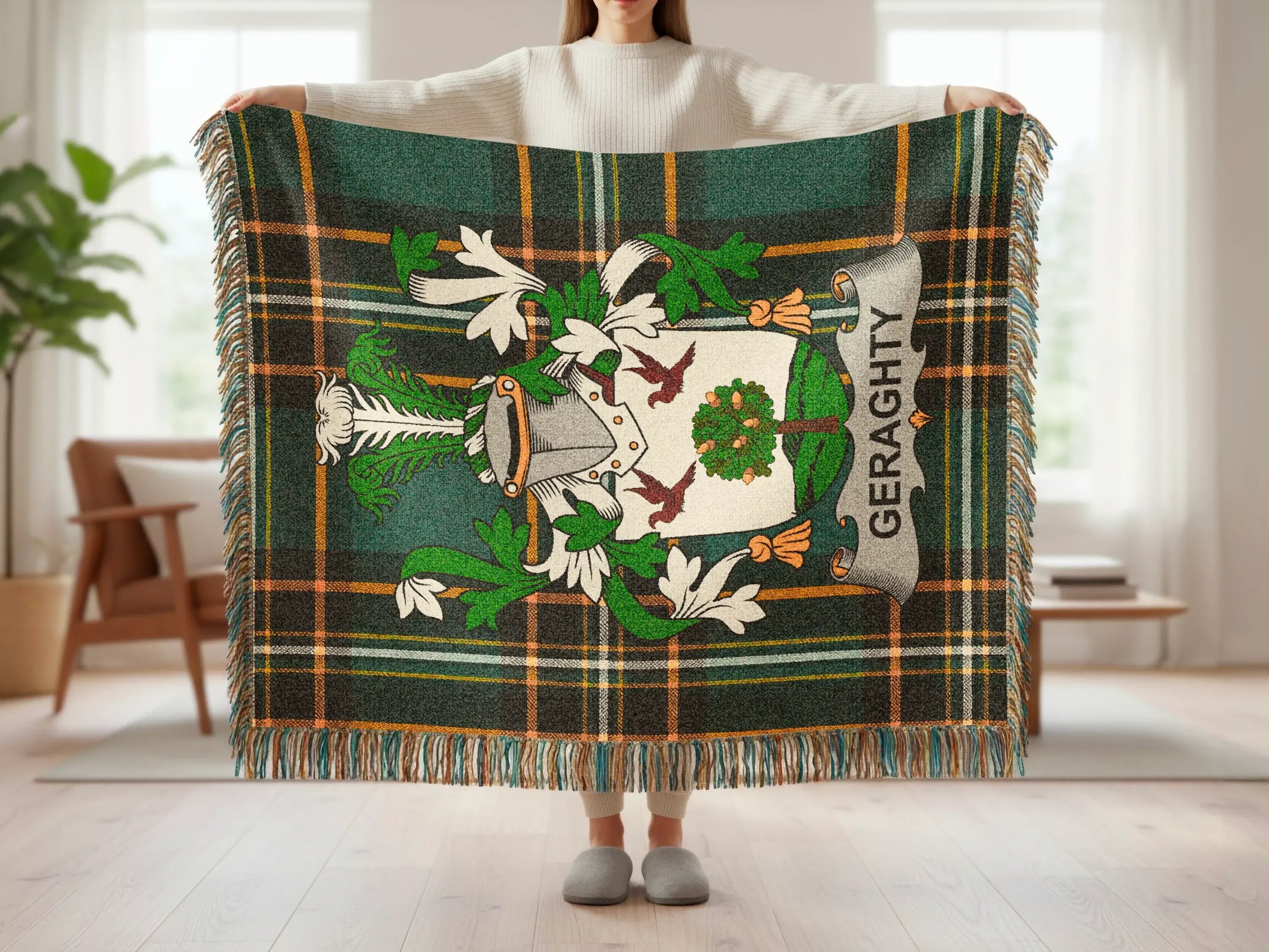 Green tartan blanket with Geraghty crest and fringe held by person.