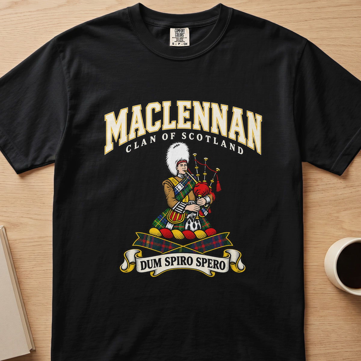 MacLennan clan crest with tartan-clad piper on a black Comfort Colors T-shirt, front view