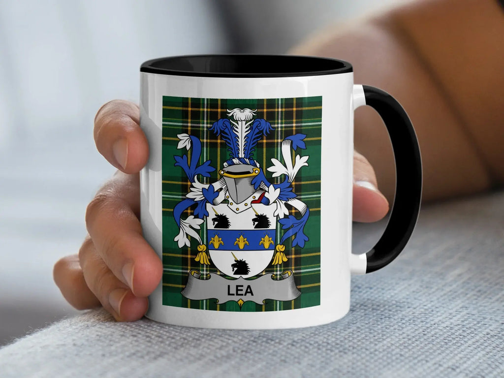 White mug with black rim featuring a green tartan pattern and a coat of arms with "LEA" below.