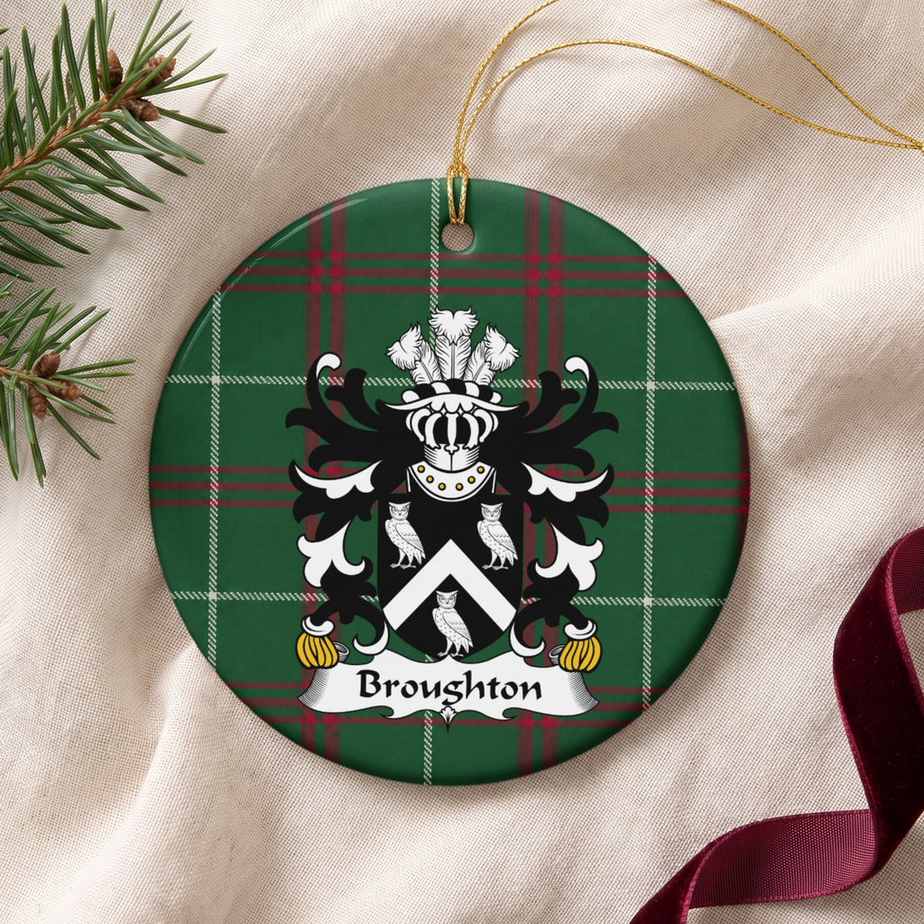 Broughton ornament on cream fabric with gold string, evergreen and burgundy ribbon; a white chevron between three white owls on black on Welsh national tartan.