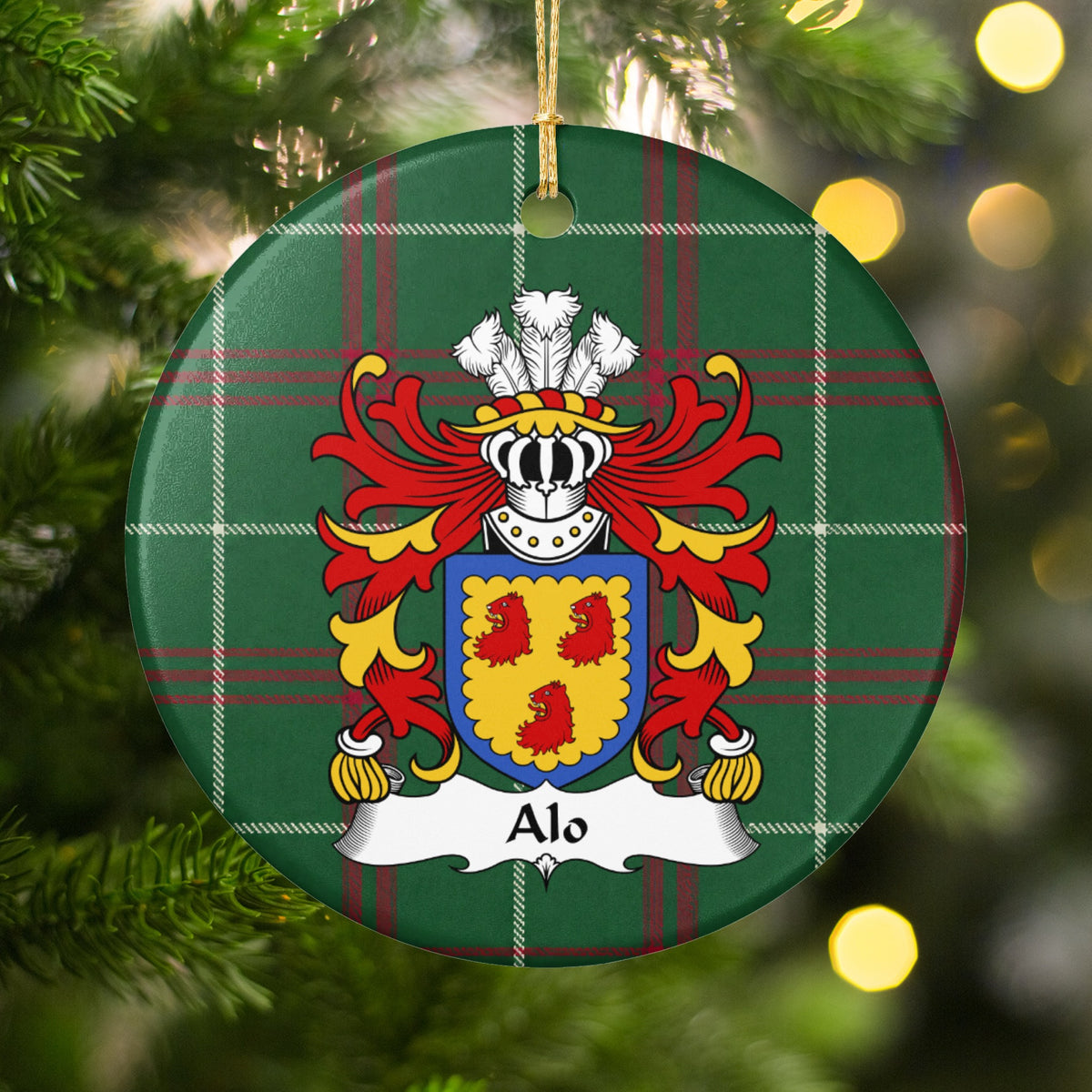 Alo family crest and surname on a round Welsh national tartan ornament, hanging by a gold cord among Christmas tree branches and warm golden lights.