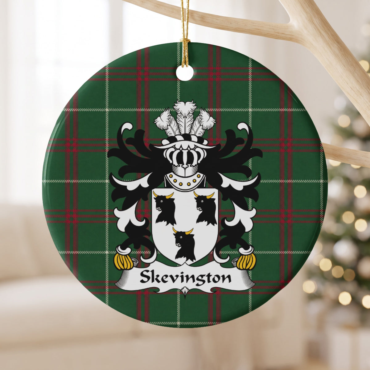 Skevington ceramic ornament with white shield with three black bull heads and gold horns on Welsh National Tartan, hanging beside a pale branch.