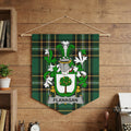Flanagan family crest on green tartan pennant hanging on a wooden wall.