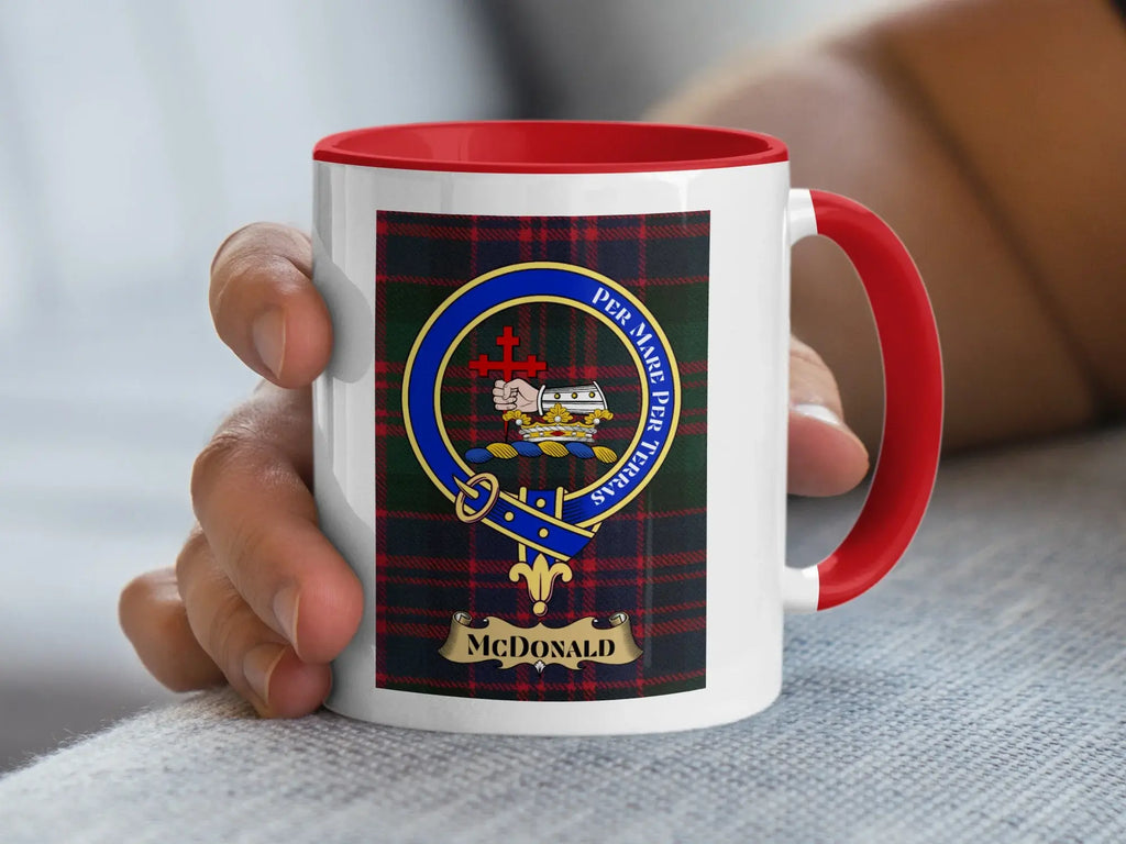 Red-handled mug with McDonald tartan and crest held by a hand.